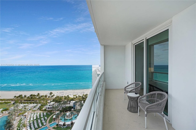 balcony with a water view and a view of the beach