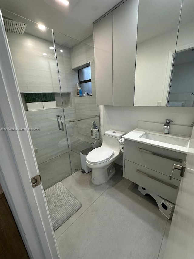 bathroom featuring vanity, toilet, and a shower with shower door