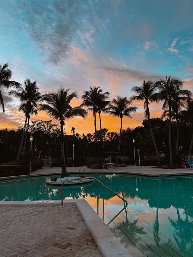 pool at dusk featuring a patio