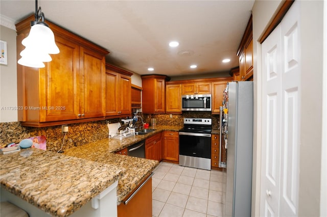 kitchen featuring a breakfast bar, pendant lighting, sink, kitchen peninsula, and stainless steel appliances