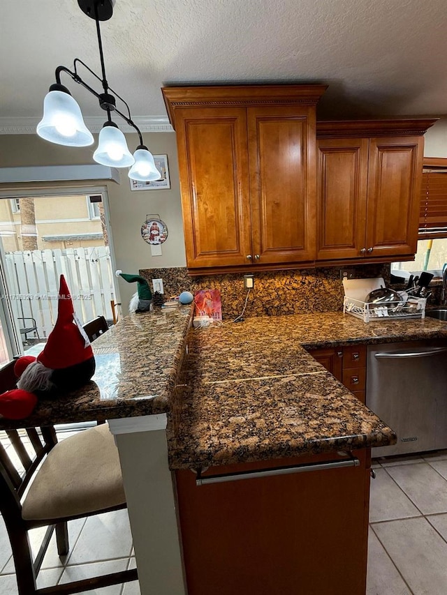 kitchen with crown molding, a breakfast bar area, dishwasher, hanging light fixtures, and light tile patterned flooring