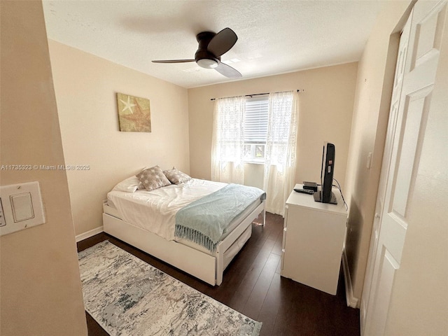 bedroom featuring dark wood-type flooring, ceiling fan, and a textured ceiling