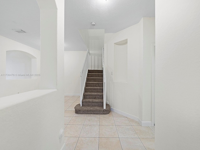 stairway featuring tile patterned flooring and a textured ceiling