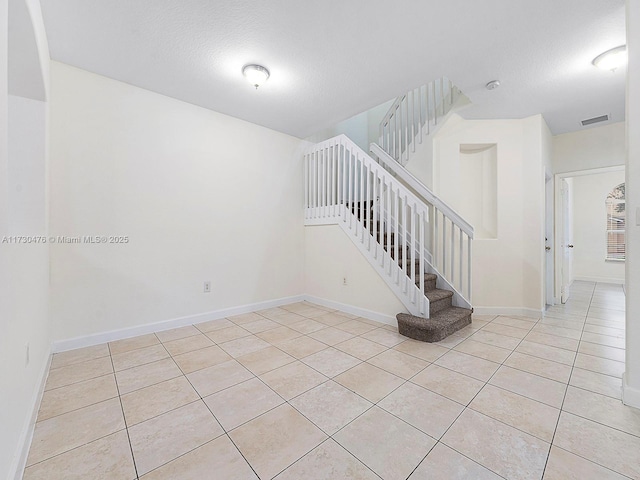 stairs featuring tile patterned flooring and a textured ceiling