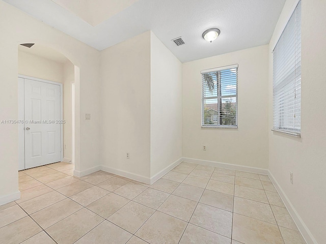 unfurnished room featuring a textured ceiling and light tile patterned floors