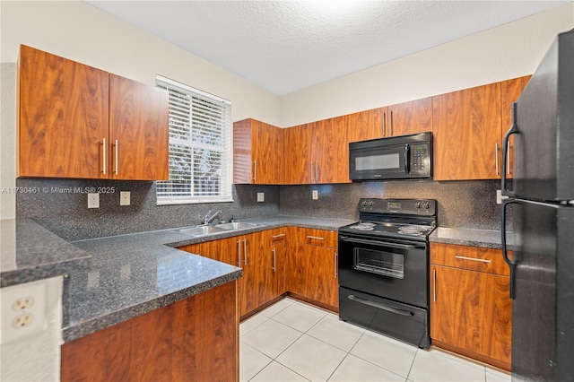 kitchen featuring tasteful backsplash, sink, light tile patterned floors, black appliances, and a textured ceiling