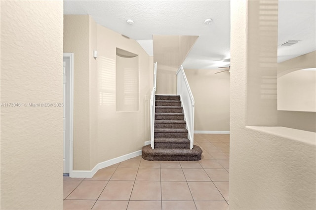 stairway with tile patterned floors and a textured ceiling