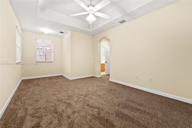 carpeted spare room with a raised ceiling and ceiling fan