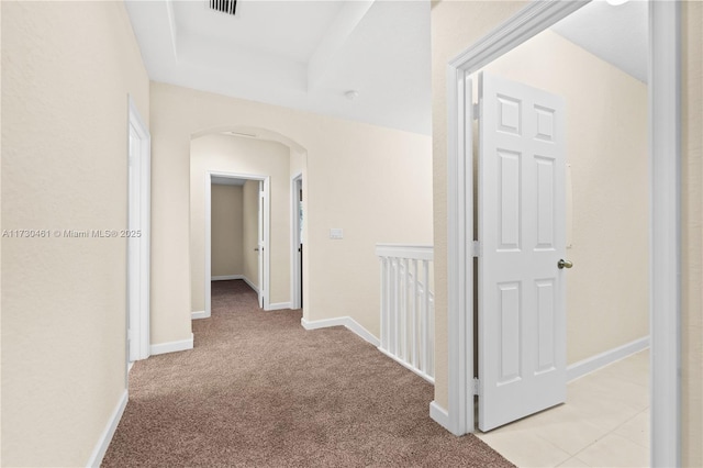 hallway with light carpet and a raised ceiling