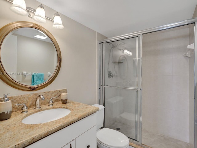 bathroom featuring vanity, a shower with door, and toilet