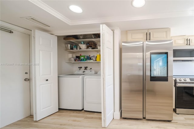 interior space with stainless steel appliances, ornamental molding, washer and clothes dryer, and light hardwood / wood-style floors