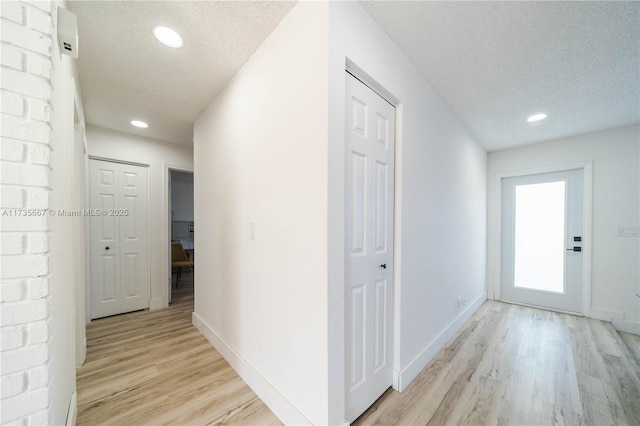 corridor featuring light hardwood / wood-style floors and a textured ceiling