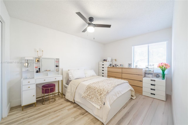 bedroom featuring ceiling fan, light hardwood / wood-style floors, and a textured ceiling