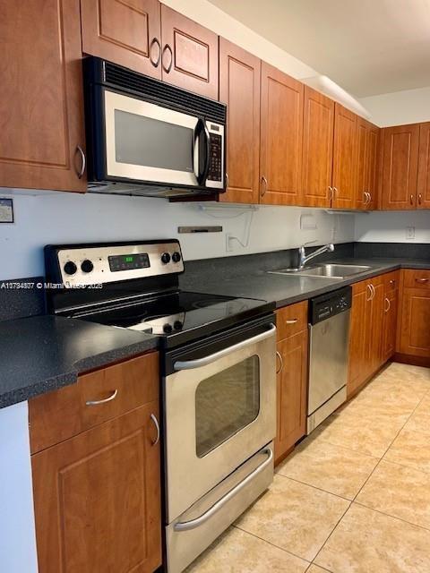 kitchen with sink, light tile patterned flooring, and appliances with stainless steel finishes