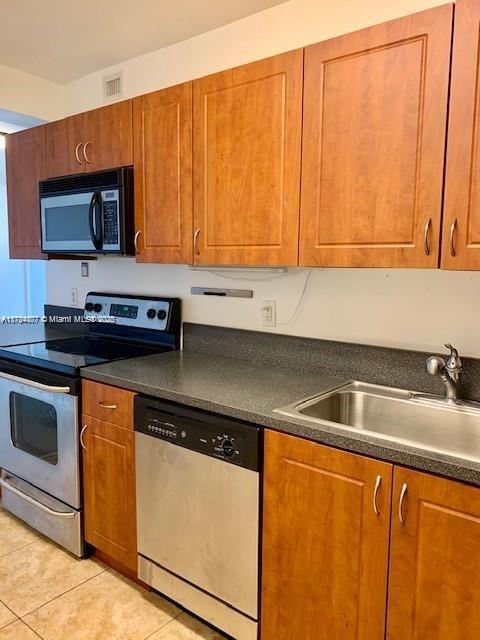 kitchen featuring stainless steel appliances, sink, and light tile patterned floors