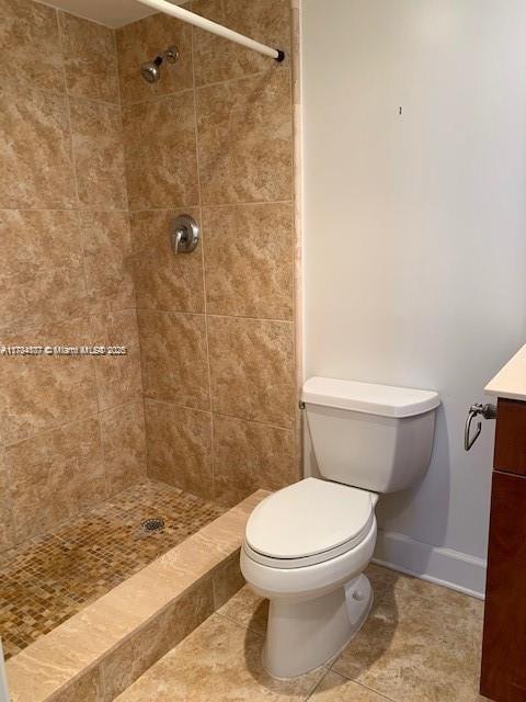 bathroom featuring vanity, toilet, and a tile shower