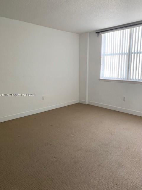 carpeted spare room with a textured ceiling