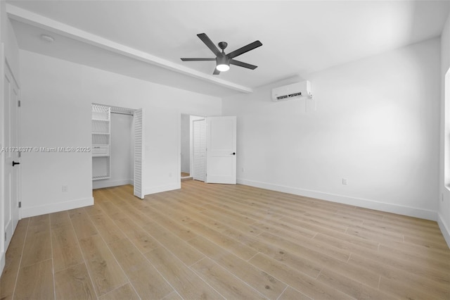 unfurnished bedroom with ceiling fan, a wall unit AC, and light hardwood / wood-style flooring