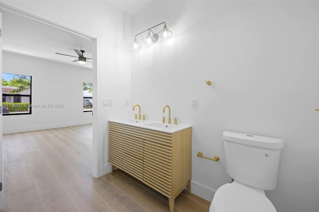 bathroom featuring hardwood / wood-style flooring, ceiling fan, vanity, and toilet