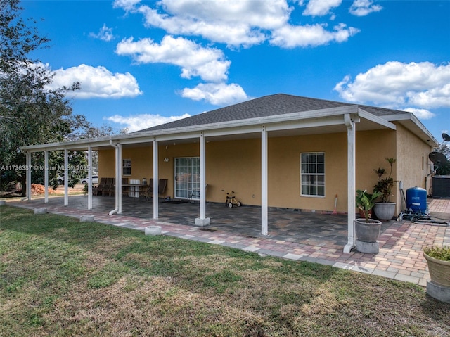 rear view of house featuring a lawn and a patio