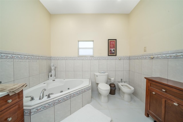 bathroom with tile patterned floors, toilet, a bidet, vanity, and a relaxing tiled tub