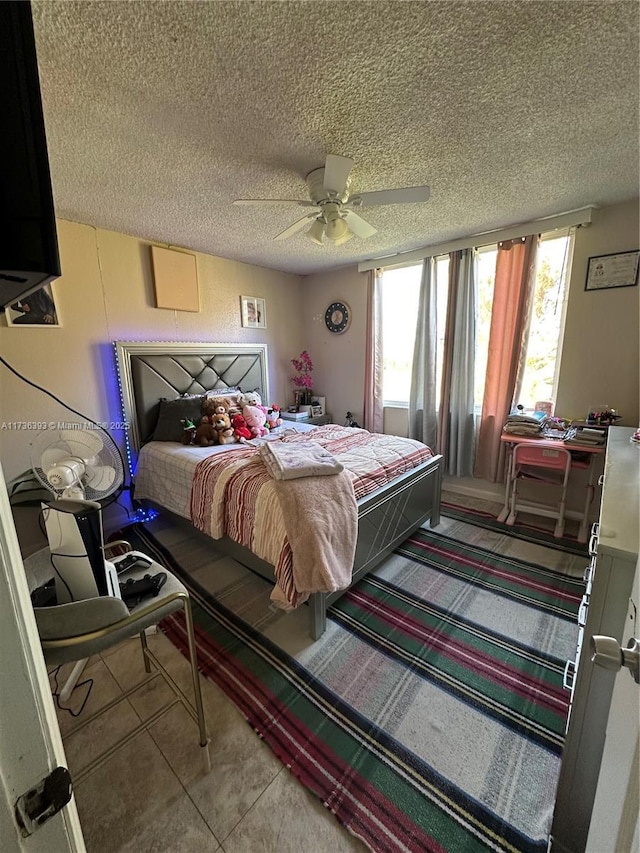 tiled bedroom with ceiling fan and a textured ceiling