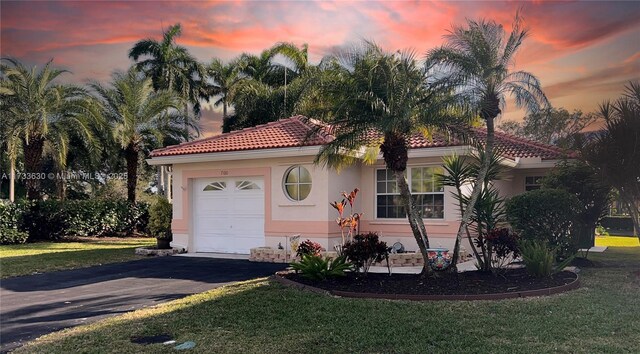 mediterranean / spanish-style home with a garage and a lawn