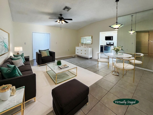 living room featuring ceiling fan, lofted ceiling, and light tile patterned floors