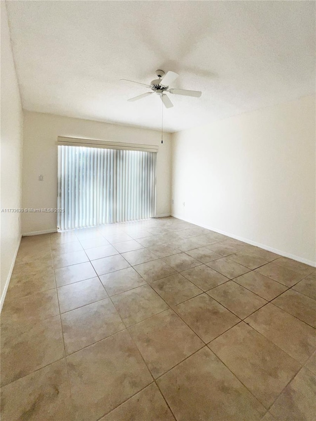 empty room with ceiling fan and light tile patterned floors