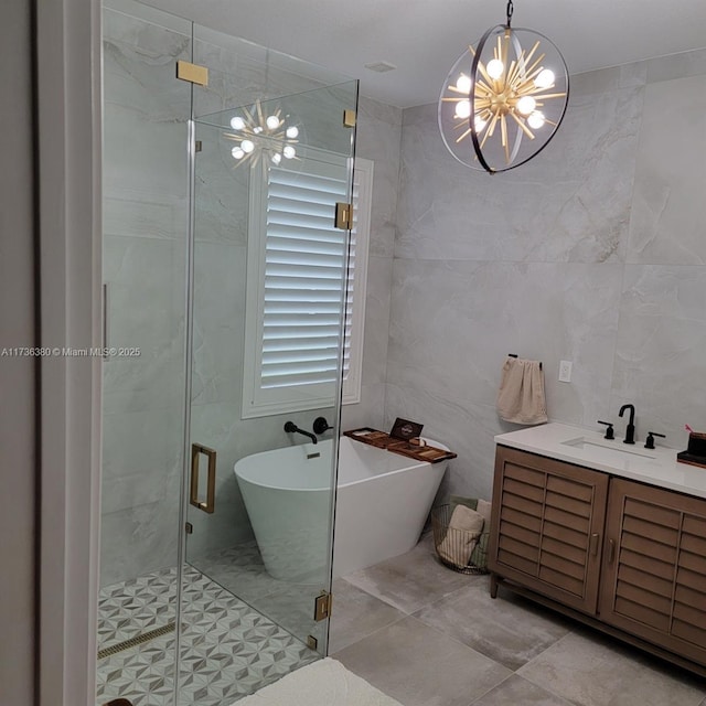 bathroom with tile walls, vanity, a notable chandelier, and separate shower and tub