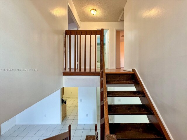 stairway featuring tile patterned flooring and a textured ceiling