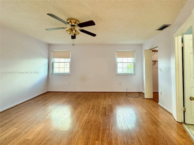 spare room with ceiling fan, plenty of natural light, a textured ceiling, and light hardwood / wood-style floors