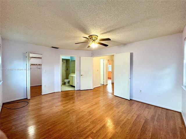 unfurnished bedroom with ceiling fan, ensuite bath, hardwood / wood-style floors, and a textured ceiling