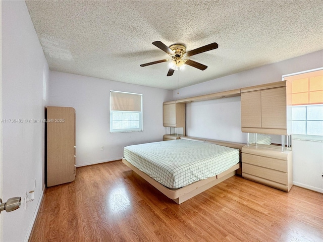 bedroom featuring ceiling fan, light hardwood / wood-style flooring, and a textured ceiling