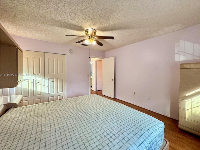 bedroom with hardwood / wood-style flooring, ceiling fan, a closet, and a textured ceiling