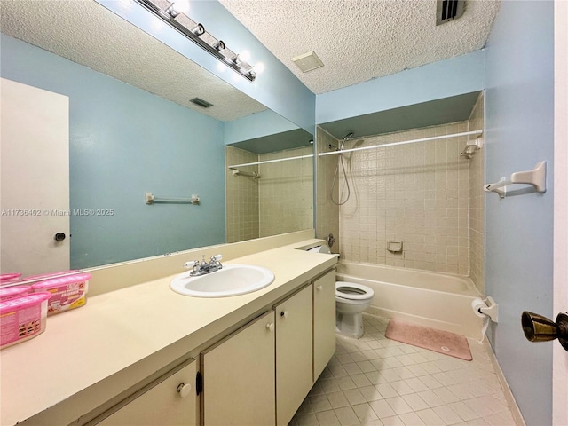 full bathroom with tile patterned floors, toilet, tiled shower / bath, a textured ceiling, and vanity