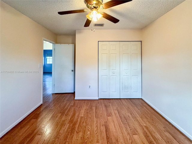 unfurnished bedroom with ceiling fan, light hardwood / wood-style floors, a closet, and a textured ceiling