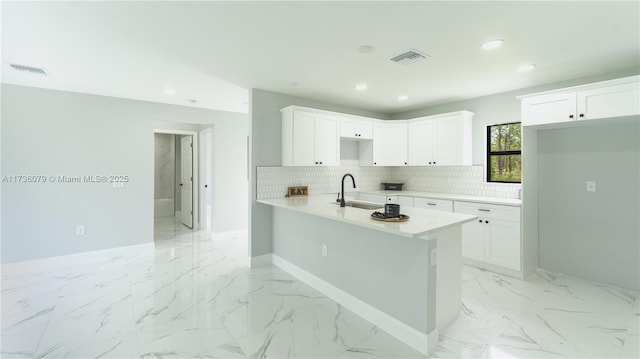 kitchen featuring tasteful backsplash, sink, kitchen peninsula, and white cabinets