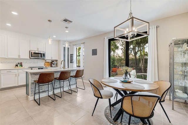 dining area featuring light tile patterned flooring, sink, and an inviting chandelier