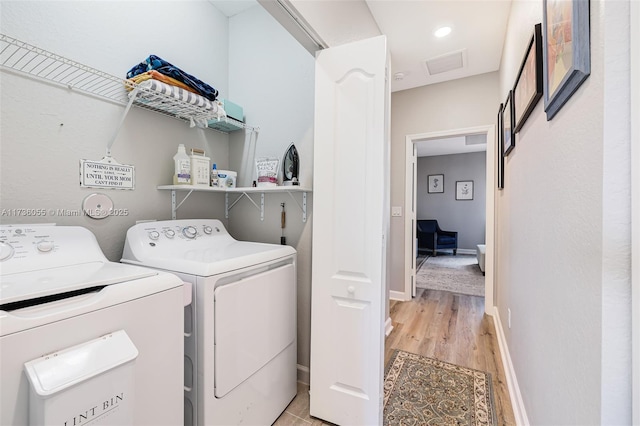 laundry area featuring washing machine and clothes dryer and light hardwood / wood-style flooring