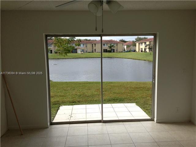 entryway featuring light tile patterned floors, ceiling fan, and a water view