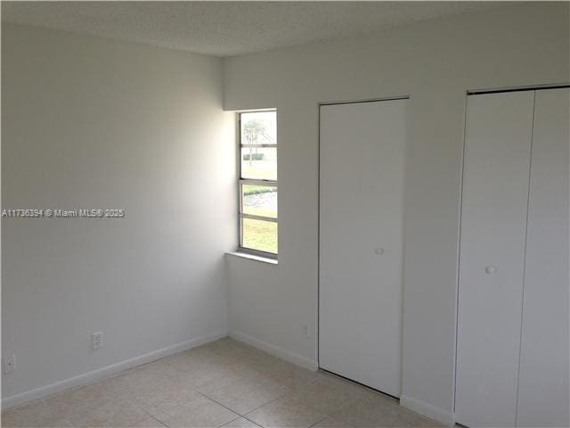 unfurnished bedroom with a textured ceiling and light tile patterned floors