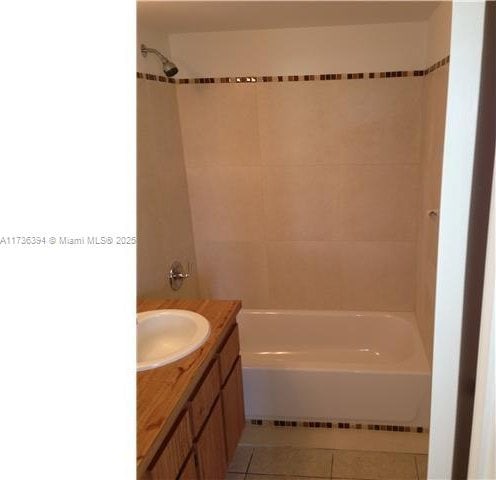 bathroom with tile patterned flooring, vanity, and tiled shower / bath combo