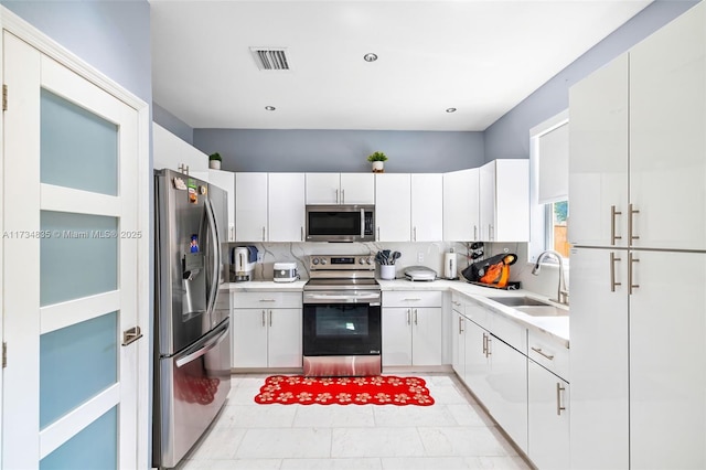 kitchen with white cabinetry, sink, tasteful backsplash, and appliances with stainless steel finishes