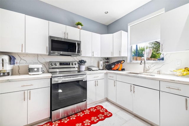 kitchen with stainless steel appliances, white cabinetry, sink, and tasteful backsplash