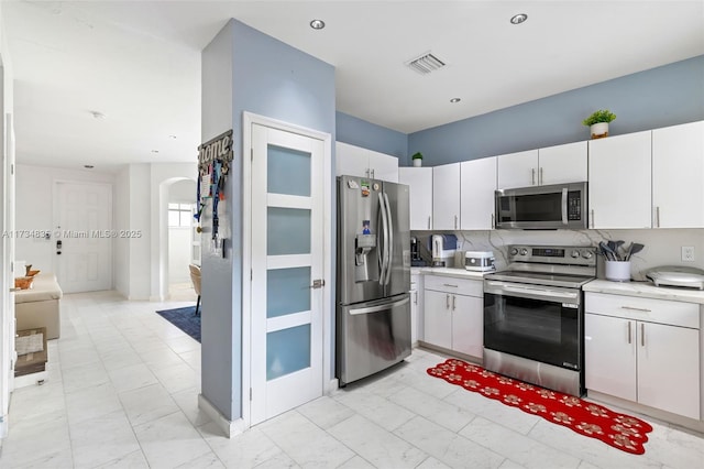 kitchen with white cabinetry, decorative backsplash, and stainless steel appliances