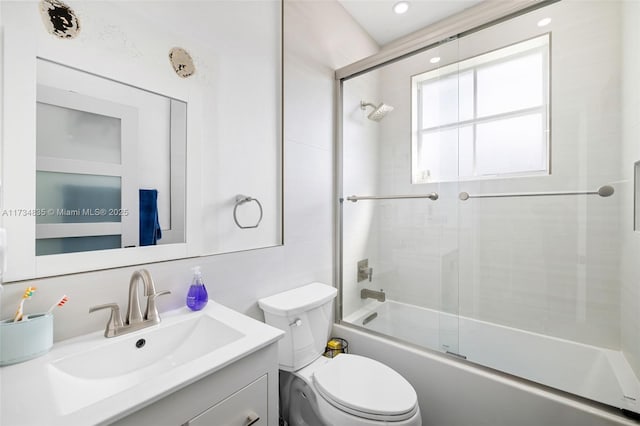 full bathroom featuring vanity, bath / shower combo with glass door, and toilet