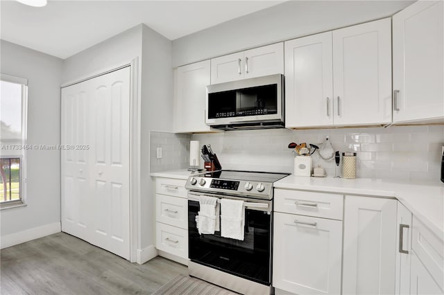 kitchen with backsplash, appliances with stainless steel finishes, light wood-type flooring, and white cabinets