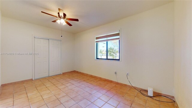 tiled bedroom featuring ceiling fan and a closet