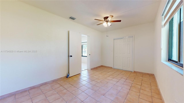 unfurnished bedroom with light tile patterned flooring, ceiling fan, and a closet